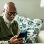 Older man, gray hair, beard, looking at smartphone, social media,